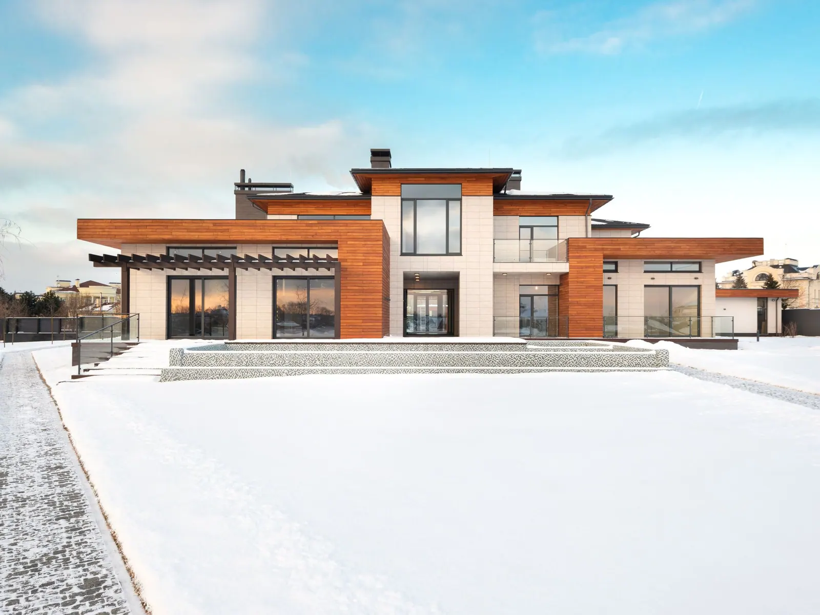 Grande maison contemporaine terminée, avec bardage en bois, grandes baies vitrées et pergola.