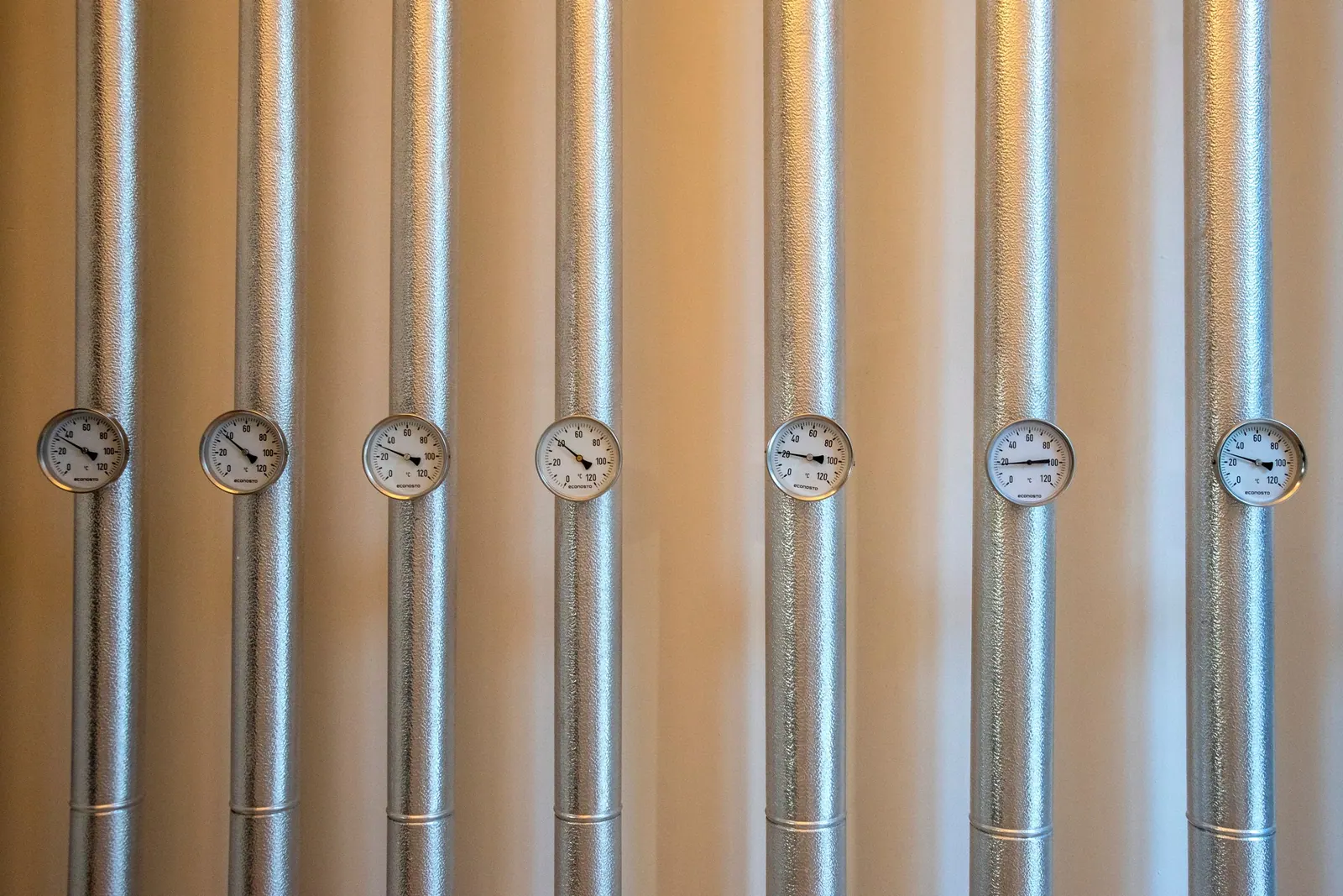 Gaines métalliques calorifugées équipées de cadrans de mesure alignés contre un mur.