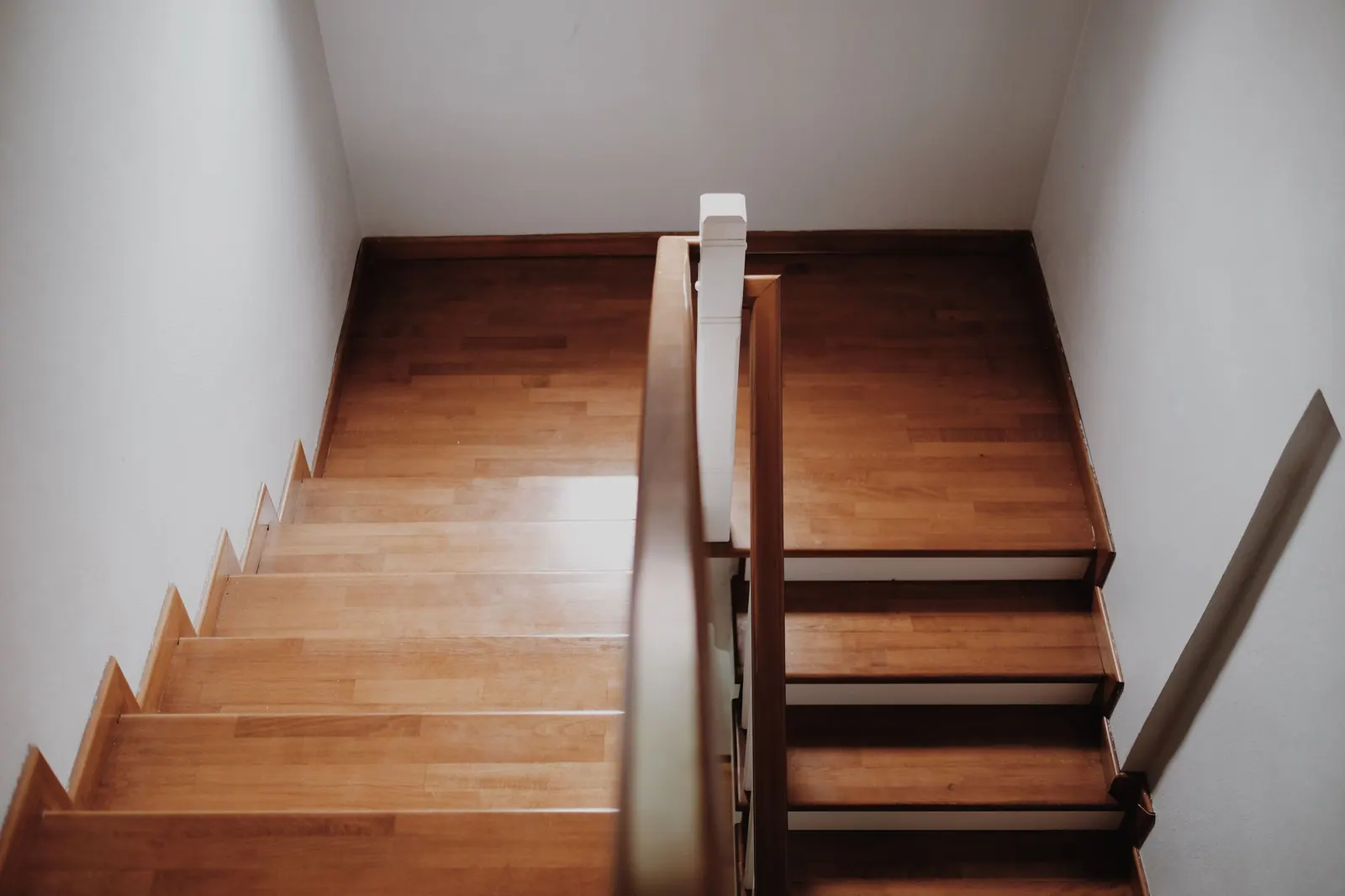 Escalier en bois vu de dessus, avec marches en bois verni et rampe à main courante.