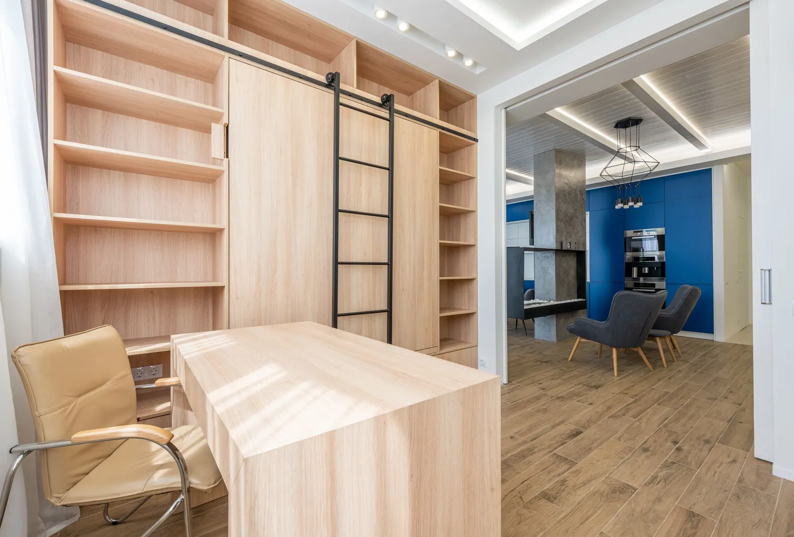 Bibliothèque sur mesure en bois clair avec échelle coulissante et bureau intégré.